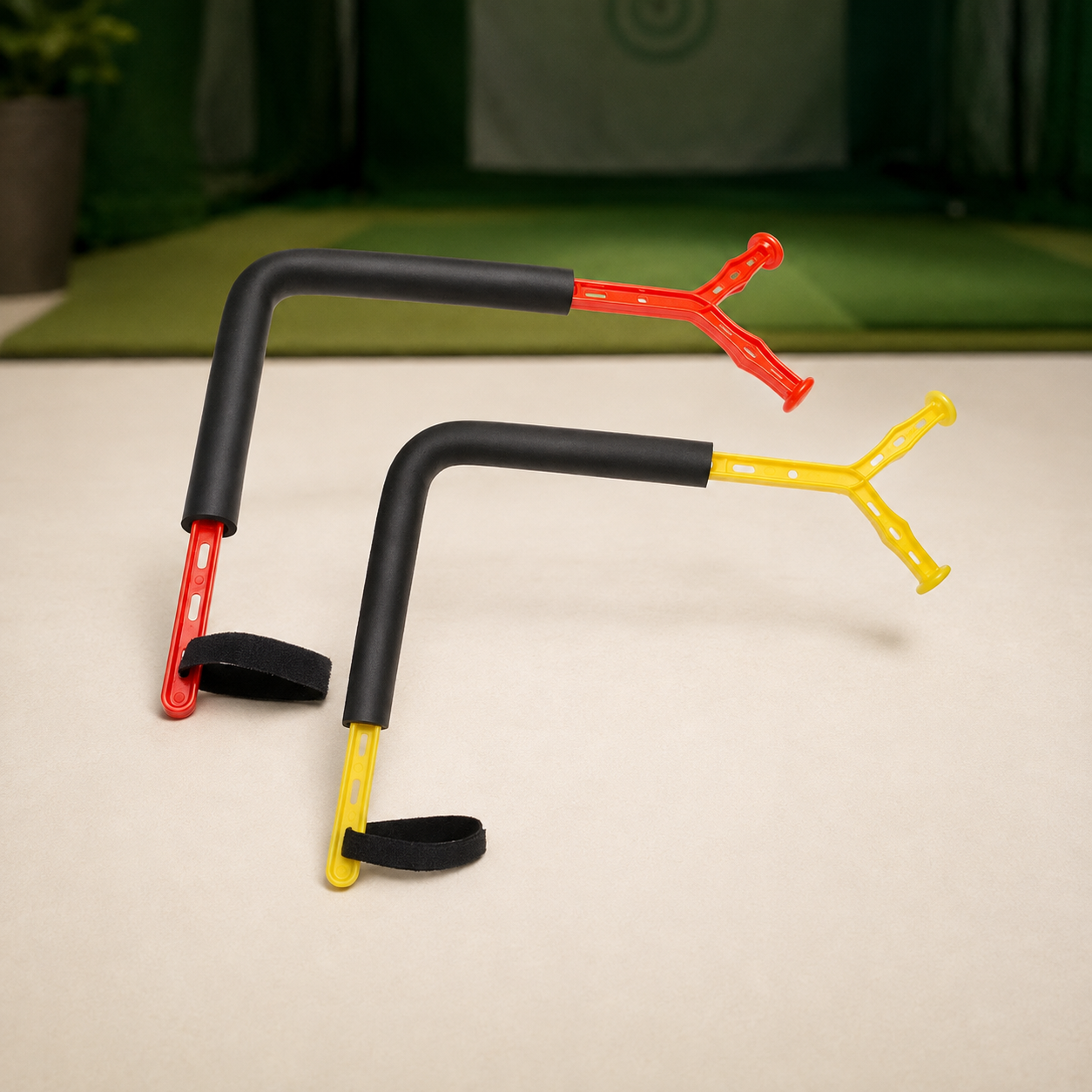 Red and yellow Rotation Trainer golf swing aids on an indoor practice surface